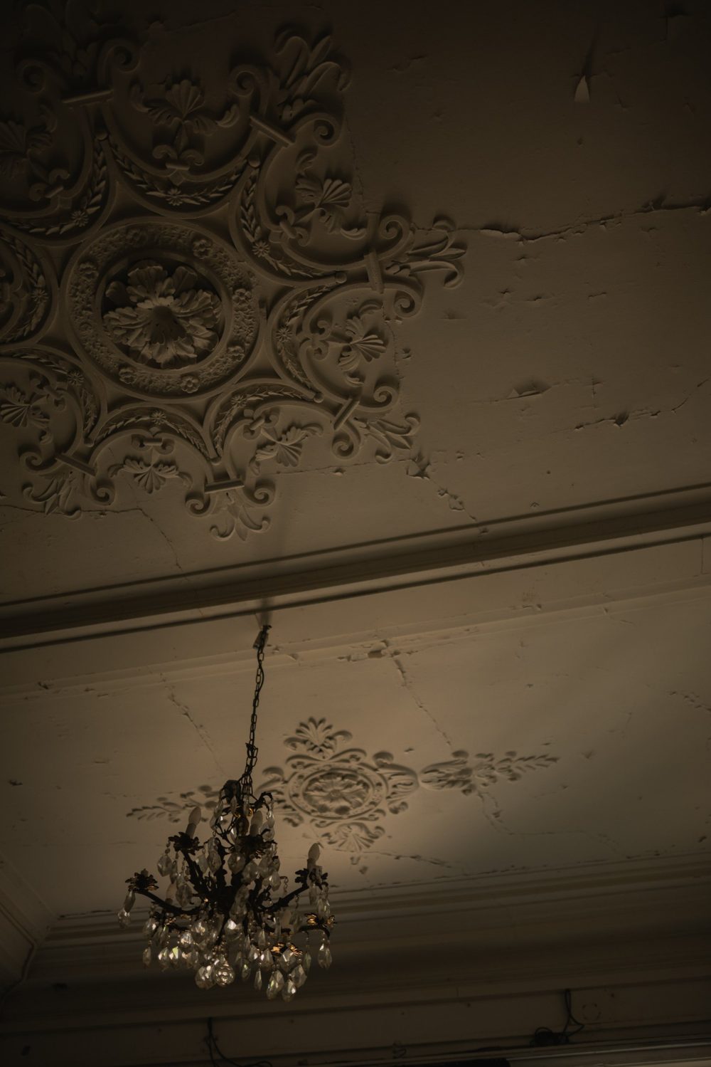 Stucplafond met ornamenten en een kroonluchter in het halfdonker